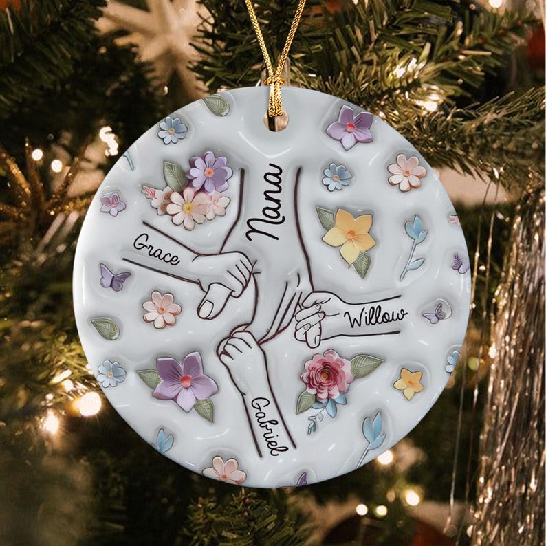 A round white ceramic ornament featuring a central illustration of four hands holding each other. The names Nana, Grace, Willow, and Gabriel are printed on the arms.