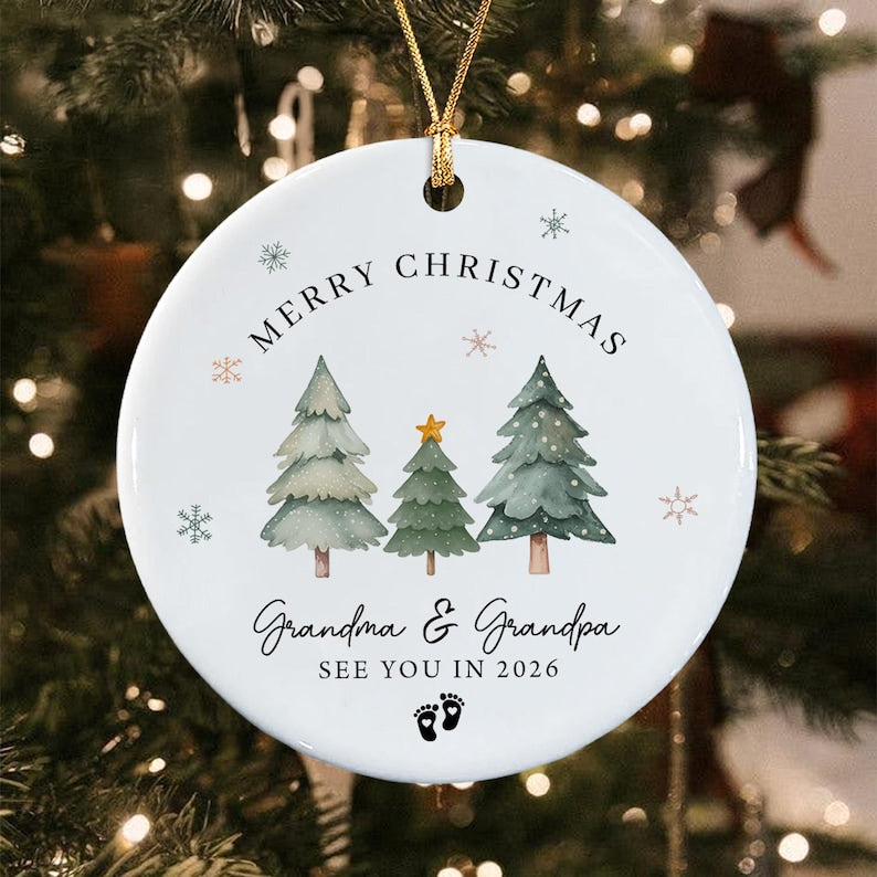 A round white ceramic Christmas ornament featuring three watercolor pine trees, a gold star, and snowflakes.