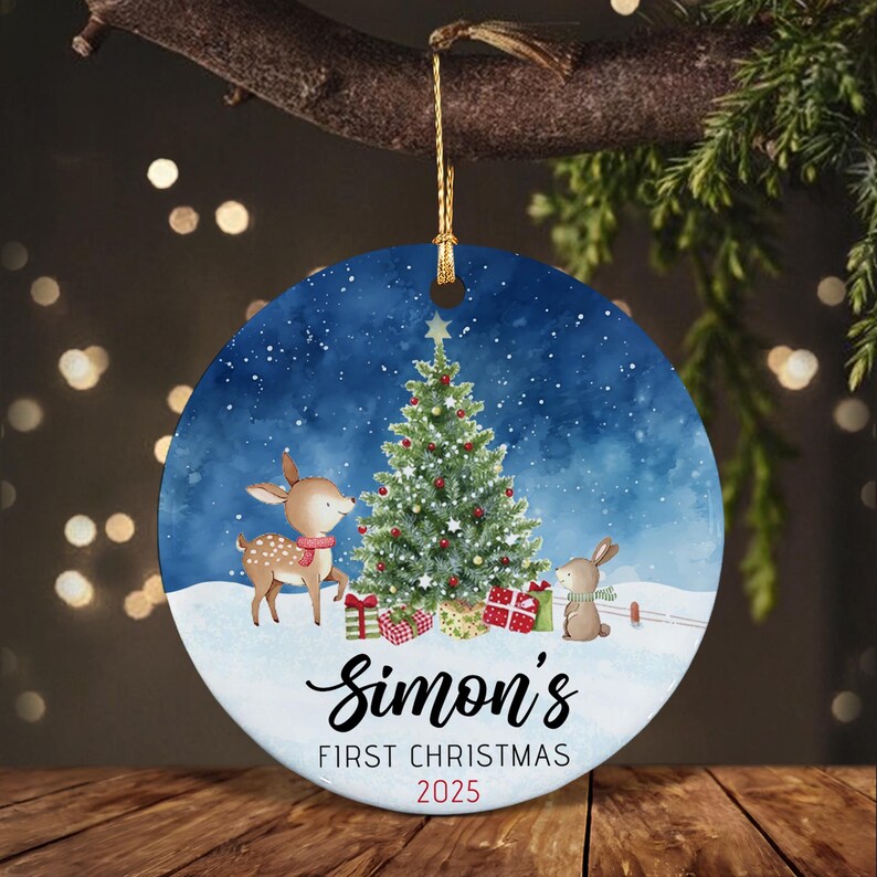 A round ceramic Christmas ornament featuring a watercolor illustration of a deer and a rabbit standing by a decorated tree in the snow.
