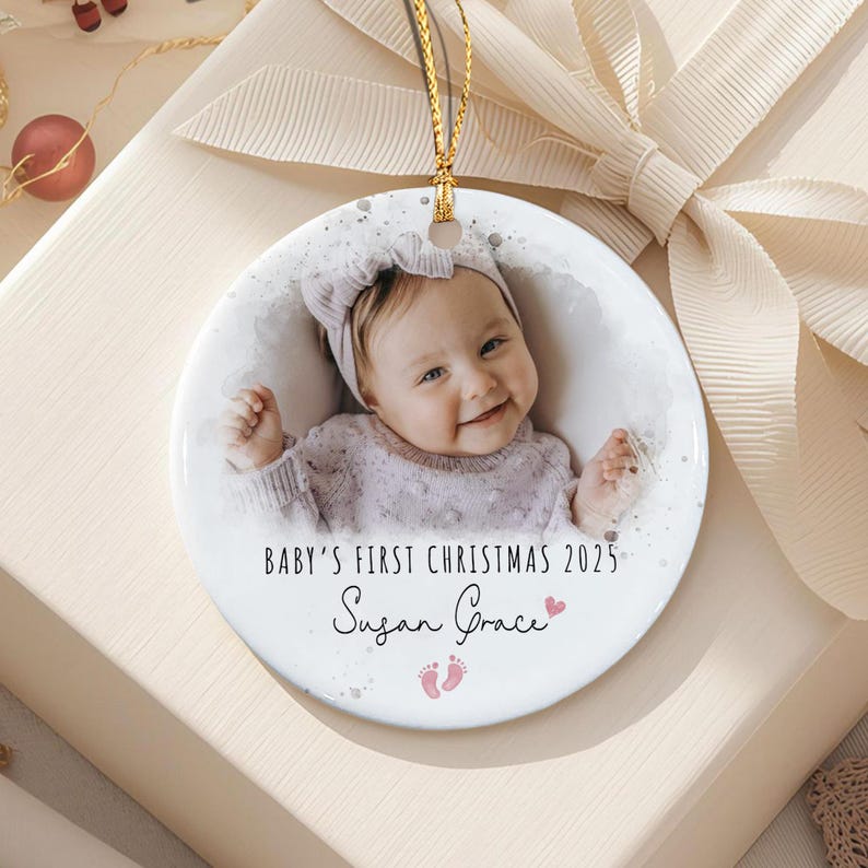 A round white ceramic ornament featuring a photograph of a baby wearing a headband and a textured sweater.