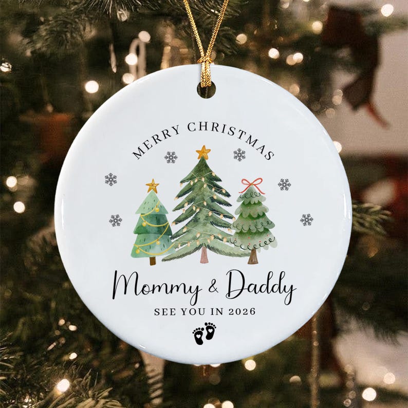 A round white ceramic Christmas ornament hanging by a gold string.