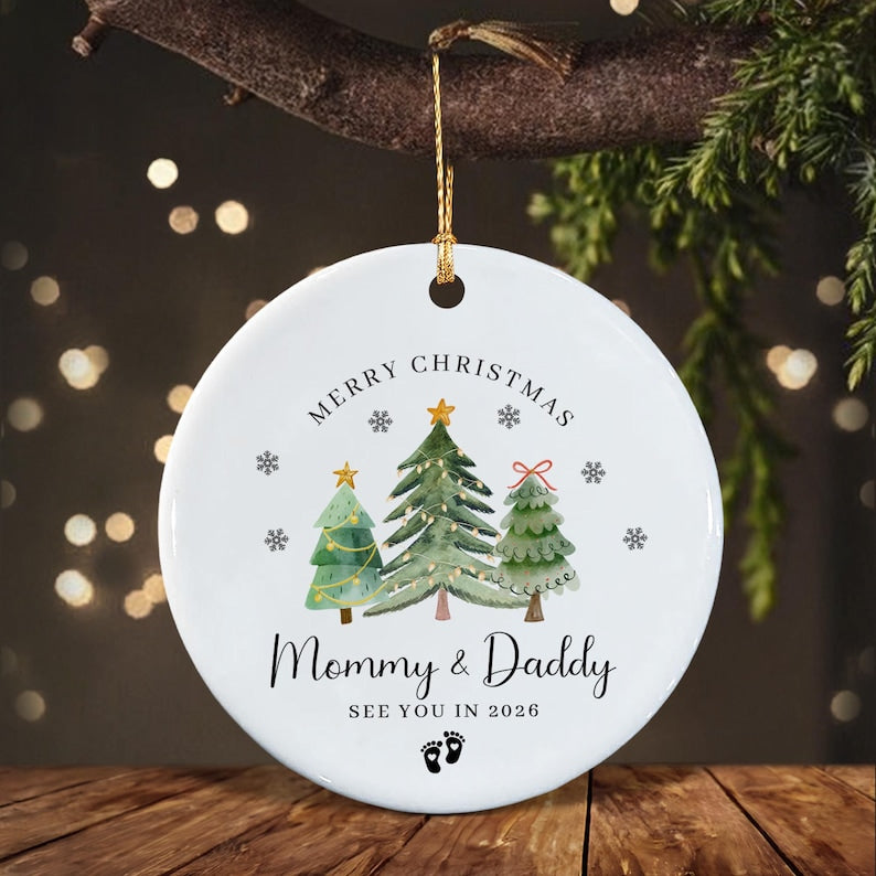 A round white ceramic Christmas ornament hanging by a gold string.