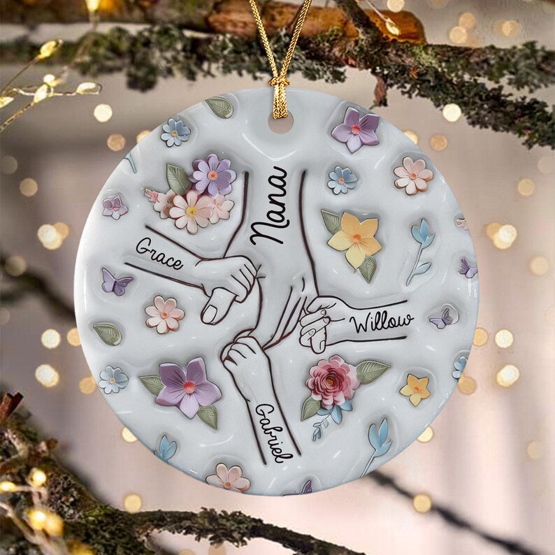 A round white ceramic ornament featuring a central illustration of four hands holding each other. The names Nana, Grace, Willow, and Gabriel are printed near the hands.