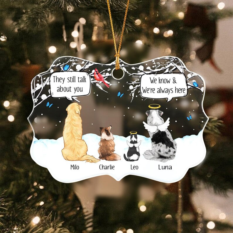 A decorative ornament featuring four pets sitting in snow under a night sky. Two pets have angel wings and halos. Speech bubbles contain the text: They still talk about you and We know & We're always here.