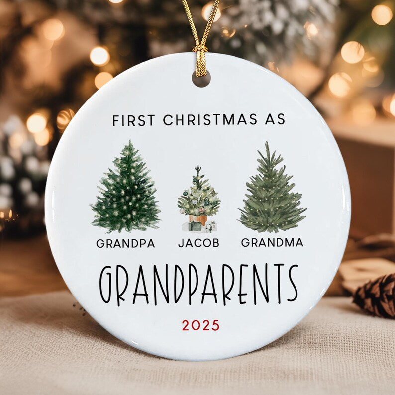 A round white ceramic ornament with a gold string. It features the text FIRST CHRISTMAS AS GRANDPARENTS, the names GRANDPA, JACOB, and GRANDMA, and the year 2025 in red.