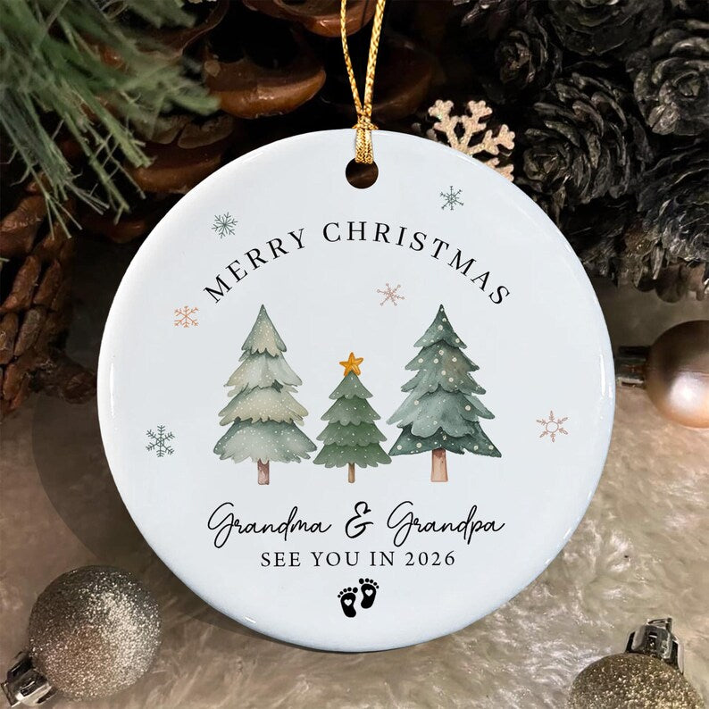 A round white ceramic Christmas ornament featuring three watercolor-style pine trees, a gold star, and small snowflakes.