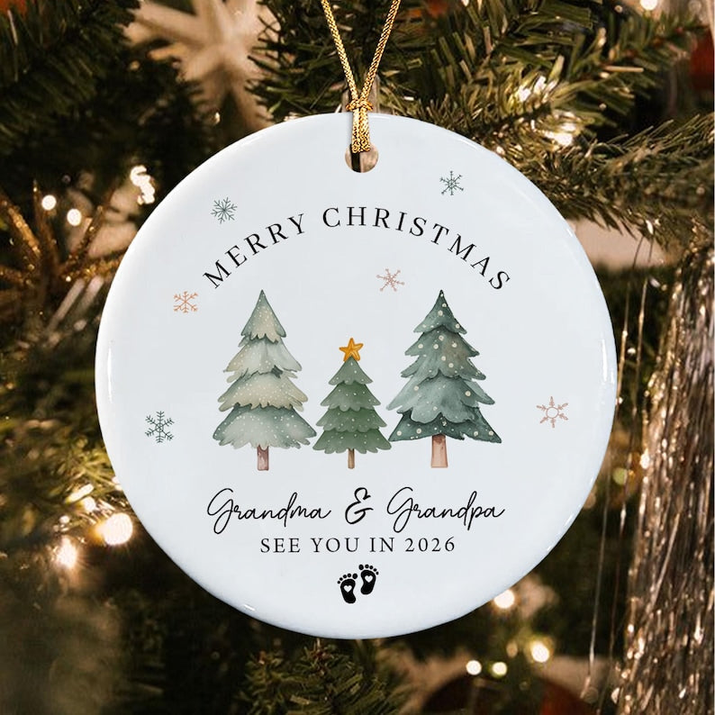 A round white ceramic Christmas ornament featuring three watercolor-style pine trees, a gold star, and snowflakes.