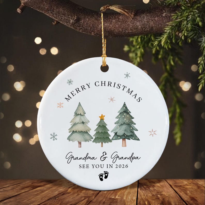 A round white ceramic Christmas ornament featuring three watercolor-style pine trees, a gold star, and small snowflakes.