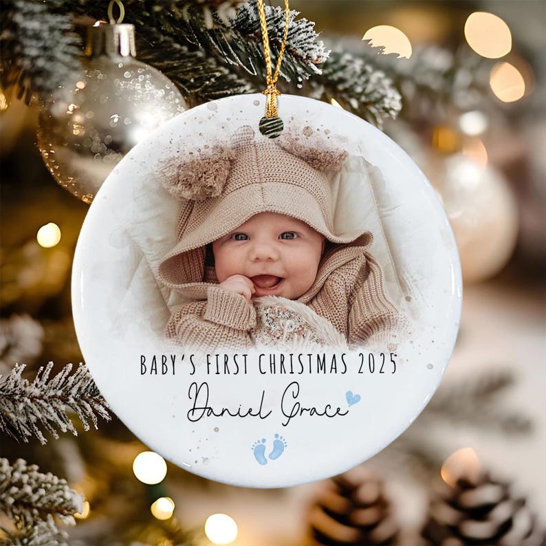 A round white ceramic ornament featuring a photograph of a smiling baby wearing a tan hooded sweater.