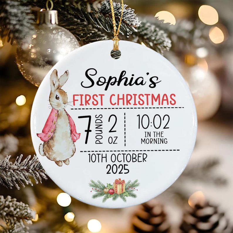 A round white ceramic Christmas ornament featuring a watercolor illustration of a rabbit in a pink jacket.