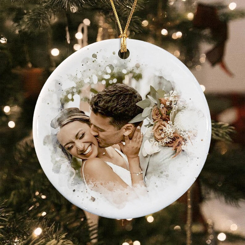 A round white ceramic ornament featuring a watercolor-style printed photograph of a couple embracing.