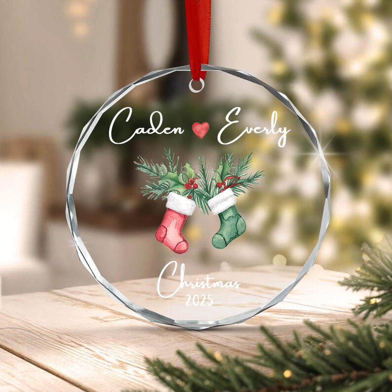A circular clear acrylic ornament with faceted edges, hanging from a red ribbon.