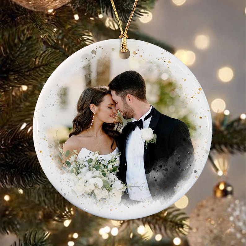 A round white ceramic ornament featuring a printed photograph of a couple in wedding attire.
