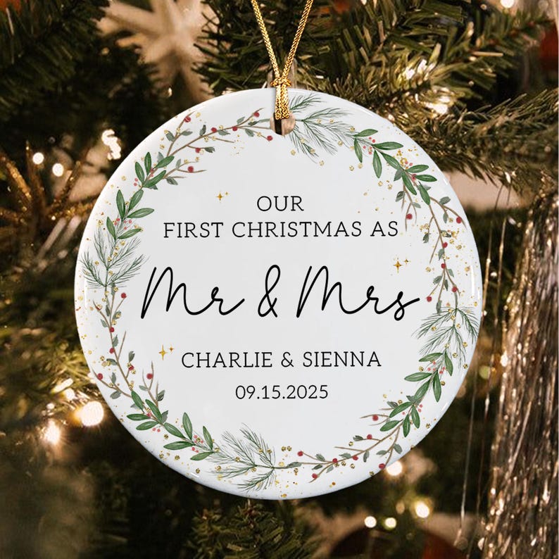 A round white ceramic ornament featuring a green pine and berry wreath design. The text reads: OUR FIRST CHRISTMAS AS Mr & Mrs CHARLIE & SIENNA 09.15.2025.