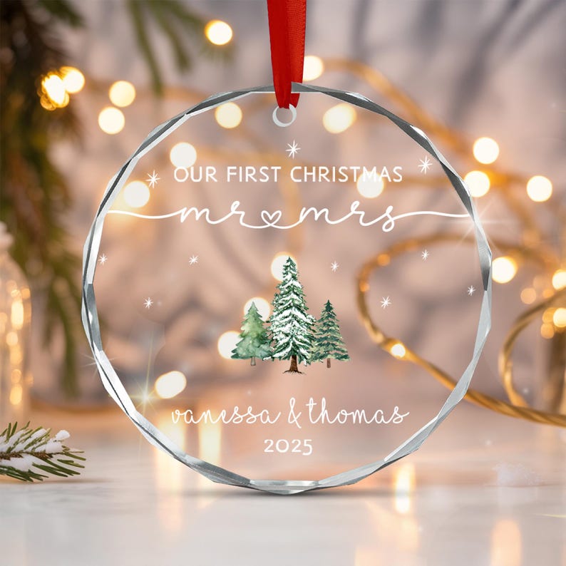 A circular clear acrylic Christmas ornament with faceted edges, hanging from a red ribbon.