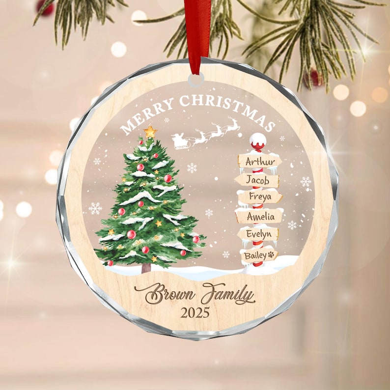 A round, clear acrylic Christmas ornament with a red ribbon hanger.