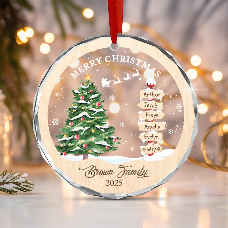 A round, clear acrylic Christmas ornament with a light wood border, featuring a printed green Christmas tree, a signpost with the names Arthur, Jacob, Freya, Amelia, Evelyn, and Bailey, Santa's sleigh.