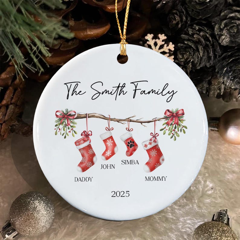 A round white ceramic Christmas ornament featuring a branch with four hanging red stockings. The text reads The Smith Family, Daddy, John, Simba, Mommy, and 2025.
