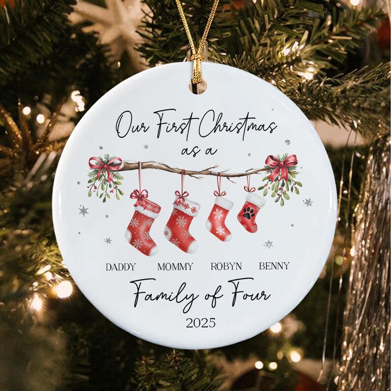 A round white ceramic Christmas ornament featuring the text Our First Christmas as a Family of Four 2025.