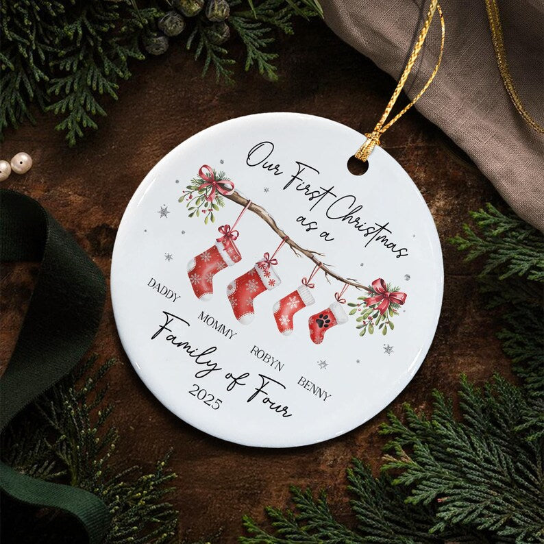 A round white ceramic ornament featuring a branch with four red Christmas stockings hanging from it.