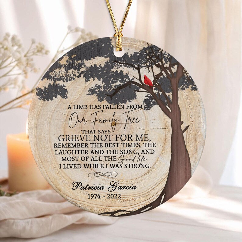A round ceramic ornament featuring a wood grain background, a dark tree silhouette, and a small red cardinal bird.