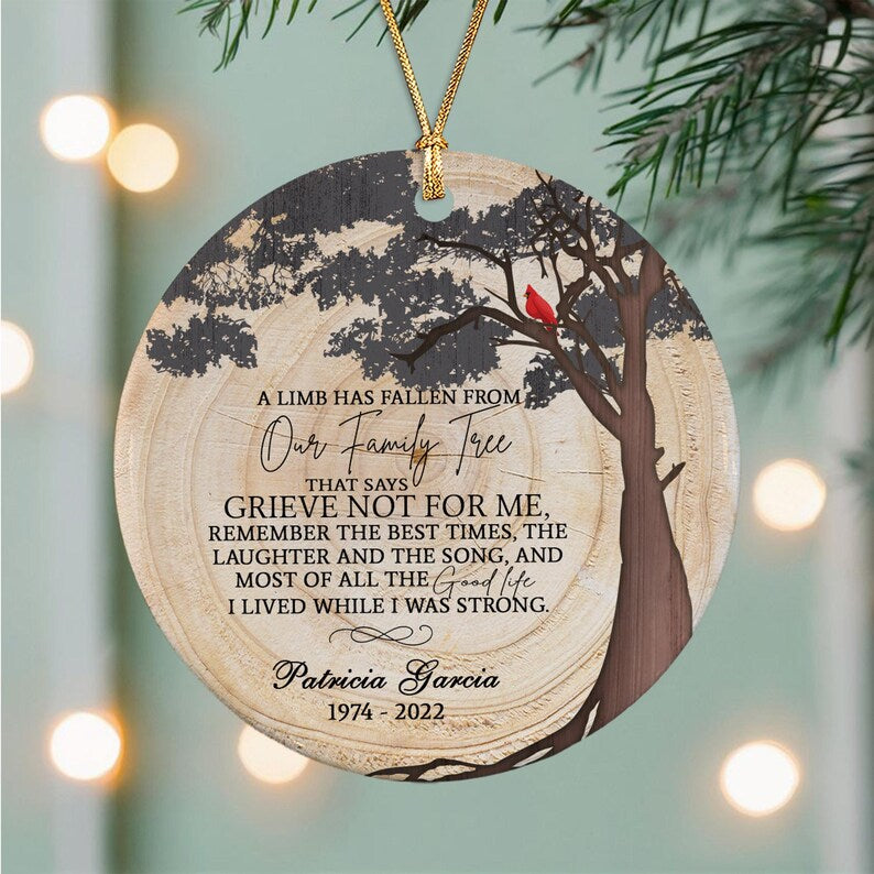 A round ceramic ornament with a wood grain texture, featuring a black tree silhouette, a red cardinal, and the text: A LIMB HAS FALLEN FROM Our Family Tree THAT SAYS GRIEVE NOT FOR ME, REMEMBER THE BEST TIMES.
