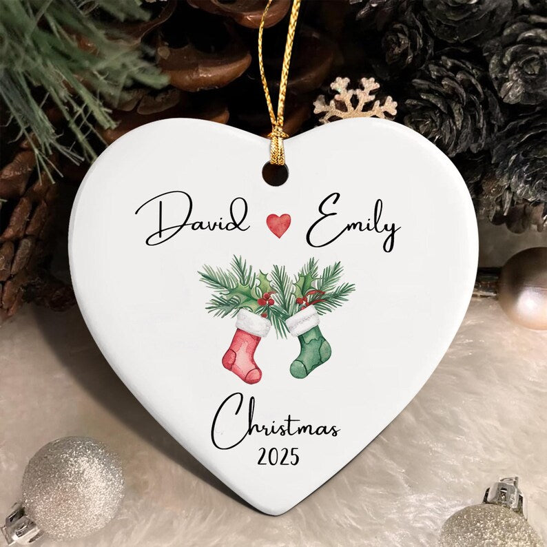 A white heart-shaped ceramic ornament featuring the names David and Emily separated by a small red heart.