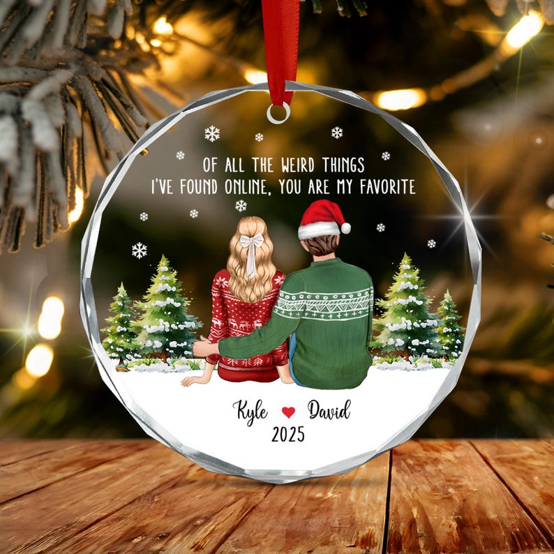 A round, faceted glass Christmas ornament with a red ribbon hanger.