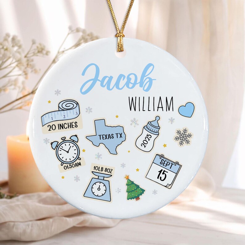 A round white ceramic ornament with a gold string featuring the name Jacob William in blue and black text.