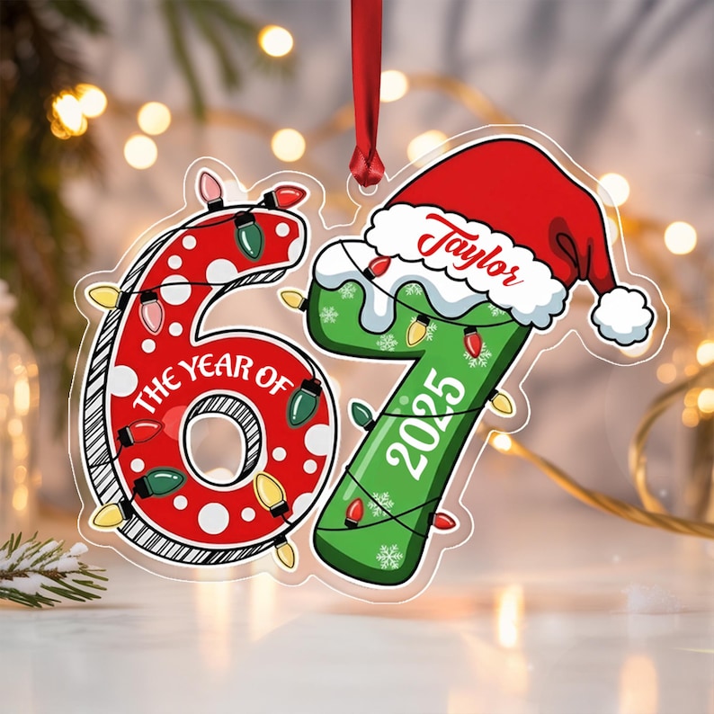 A flat, hanging Christmas ornament shaped like the number 67. The red 6 is decorated with white polka dots and the text THE YEAR OF. The green 7 features a Santa hat with the name Taylor, the year 2025, and string lights.