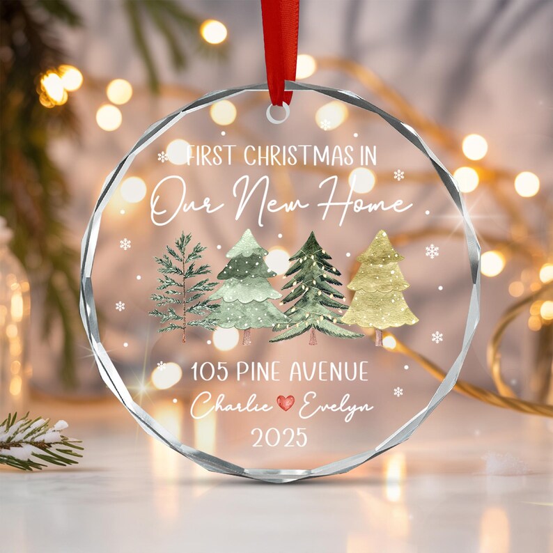 A circular clear glass ornament with a faceted edge, featuring a red ribbon hanger.