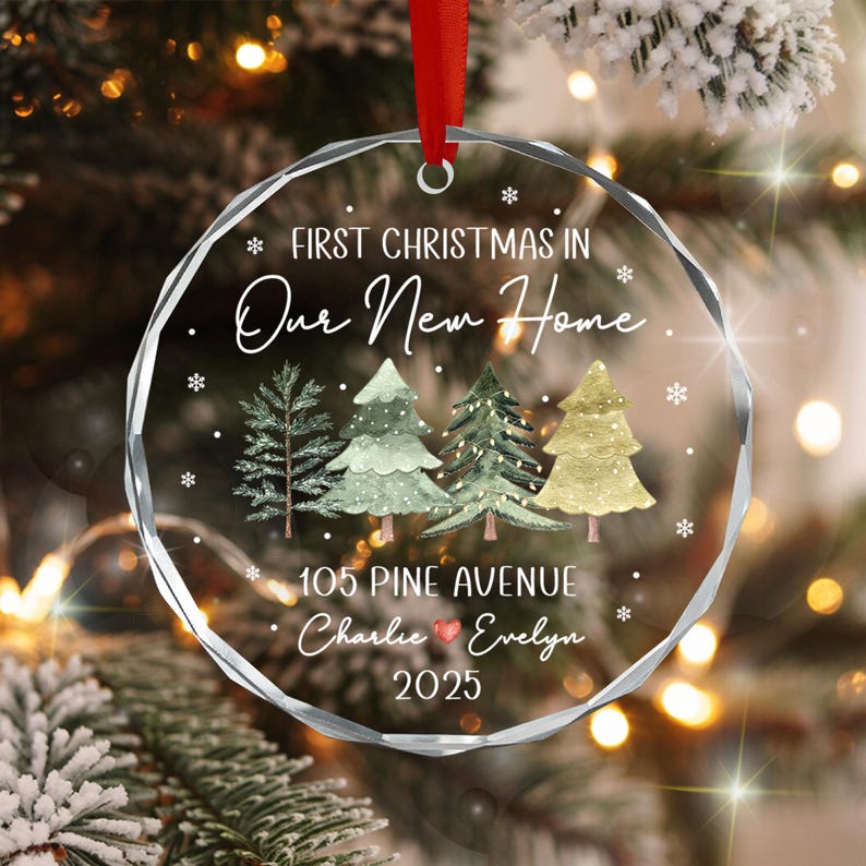 A clear, circular, faceted glass Christmas ornament hanging from a red ribbon.