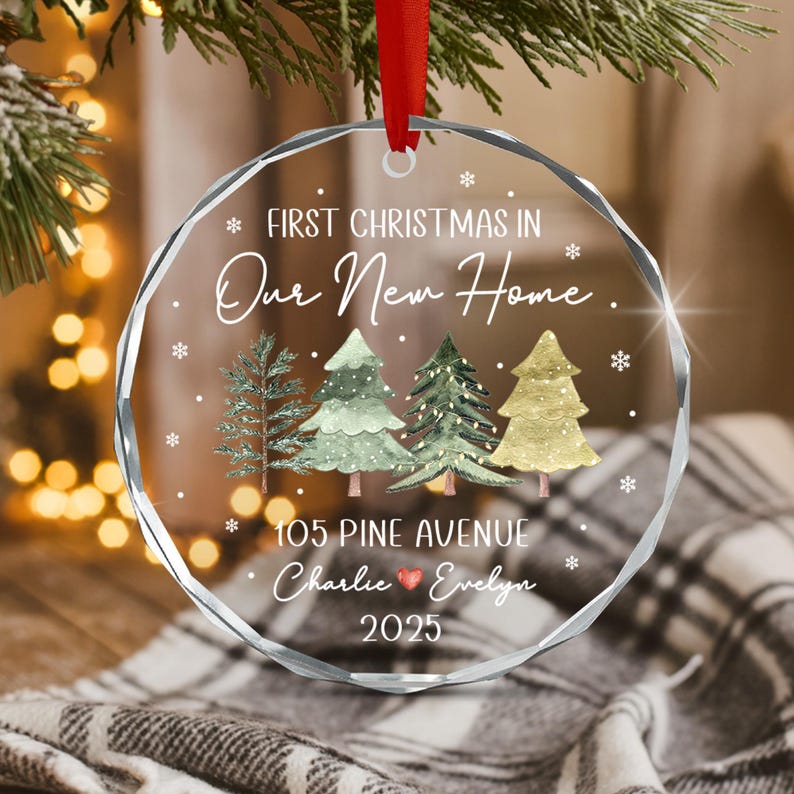 A circular clear acrylic ornament with faceted edges, featuring a red ribbon hanger.