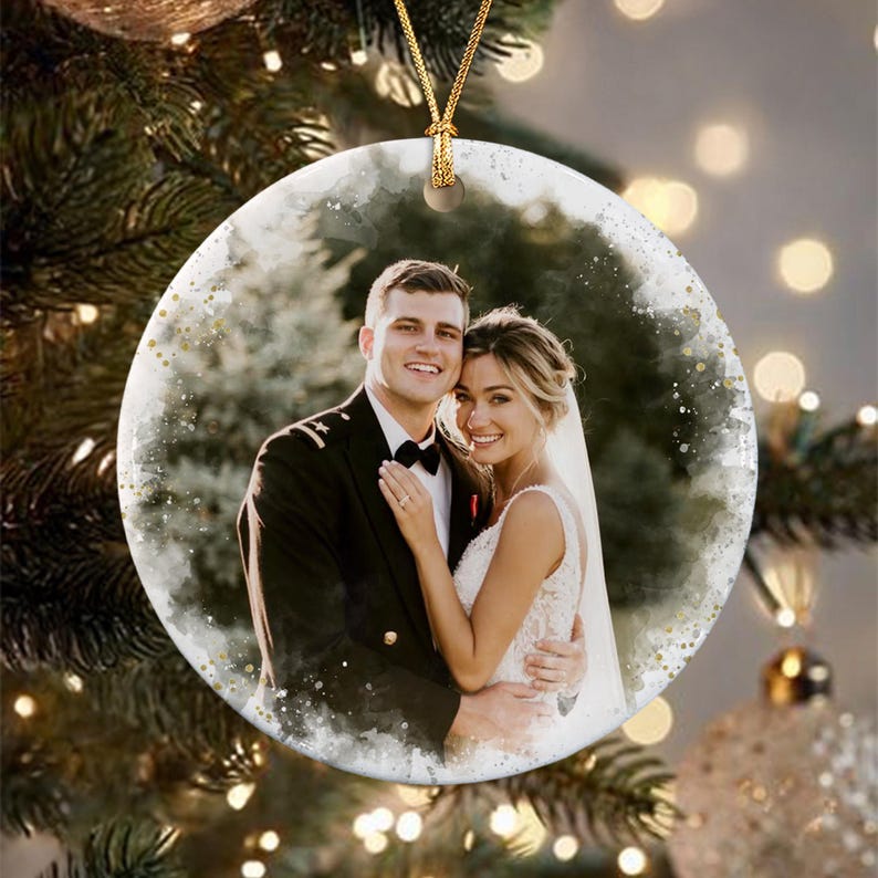 A round ceramic ornament featuring a printed photograph of a couple. The person on the left wears a dark military uniform with a black bowtie, and the person on the right wears a white lace wedding dress.