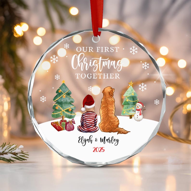 A round, clear acrylic Christmas ornament with a red ribbon.
