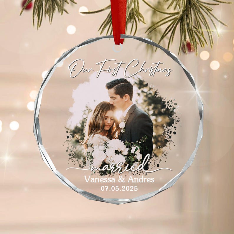 A round, faceted clear glass ornament hanging from a red ribbon.