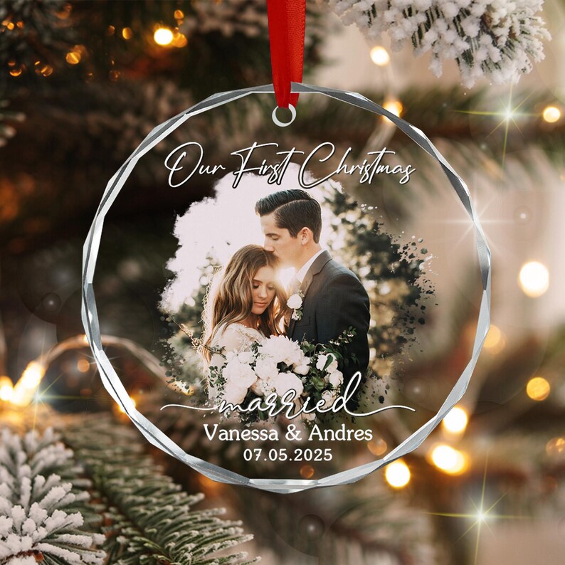 A circular, faceted glass Christmas ornament featuring a printed photograph of a couple in wedding attire. The text reads Our First Christmas, married, Vanessa & Andres, and 07.05.2025.