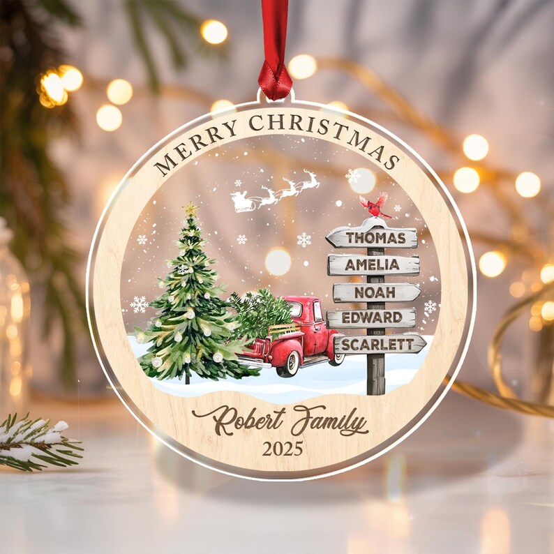A round, clear acrylic Christmas ornament with a red ribbon hanger.