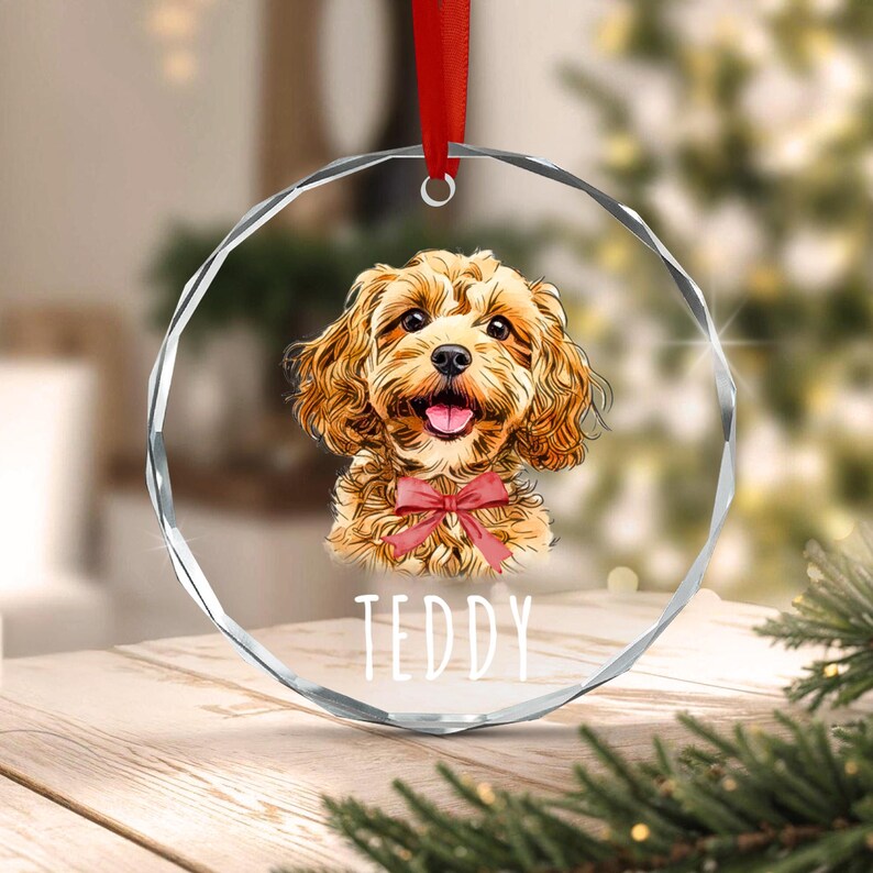 A circular, faceted glass ornament featuring a golden-brown dog illustration with a red bow tie. The name TEDDY is printed in white below the dog.