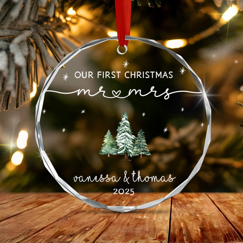 A circular, faceted clear glass Christmas ornament hanging from a red ribbon.