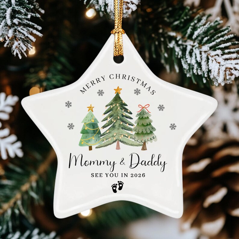 A white star-shaped ceramic Christmas ornament featuring a watercolor illustration of three pine trees, snowflakes, and the text Merry Christmas, Mommy & Daddy, SEE YOU IN 2026.
