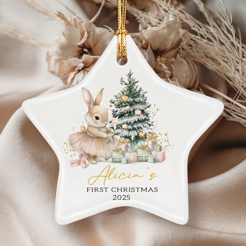 A white star-shaped ceramic ornament featuring a watercolor illustration of a rabbit in a tutu standing by a decorated Christmas tree with gifts.
