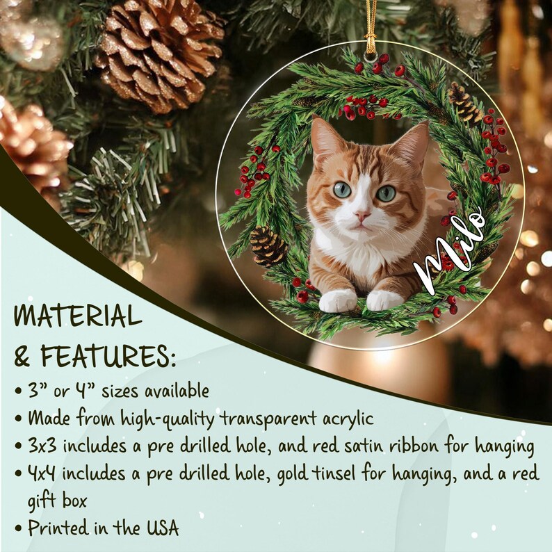 A round transparent acrylic Christmas ornament featuring a printed image of an orange and white tabby cat centered within a wreath of green pine needles, red berries, and pinecones, with the name Milo written in white script text.