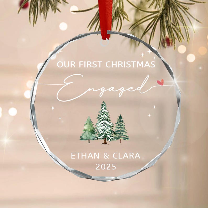 A clear, circular, faceted glass ornament hanging from a red ribbon.