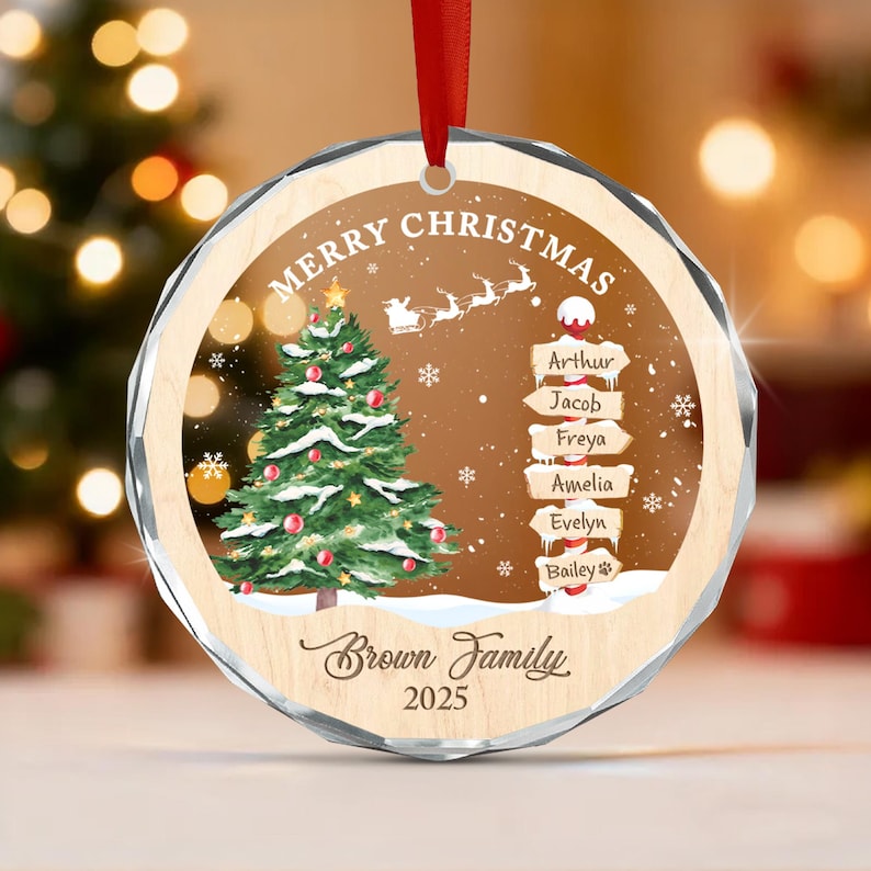A round, faceted glass Christmas ornament with a red ribbon hanger.