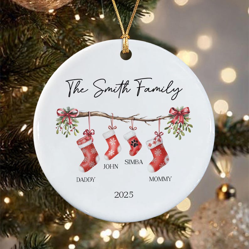 A round white ceramic Christmas ornament featuring a branch with four hanging red stockings. The text reads The Smith Family, Daddy, John, Simba, Mommy, and 2025.