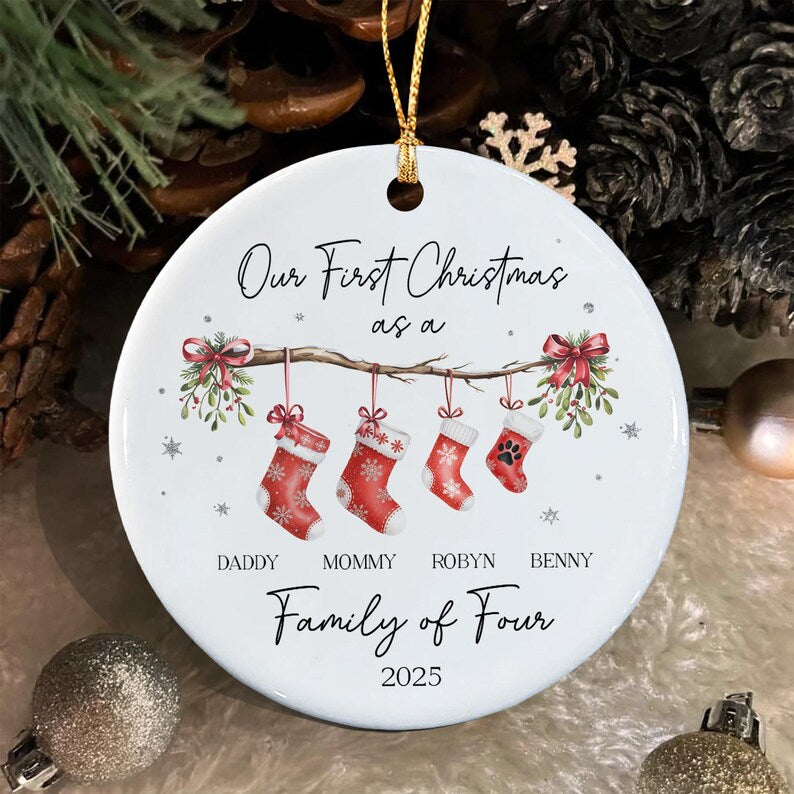 A round white ceramic Christmas ornament featuring a gold hanging string. The design shows four red stockings with white snowflake patterns hanging from a branch with mistletoe and red bows.