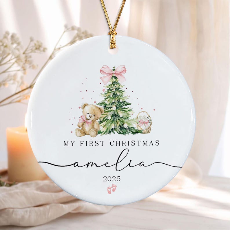 A round white ceramic ornament hanging from a gold cord.