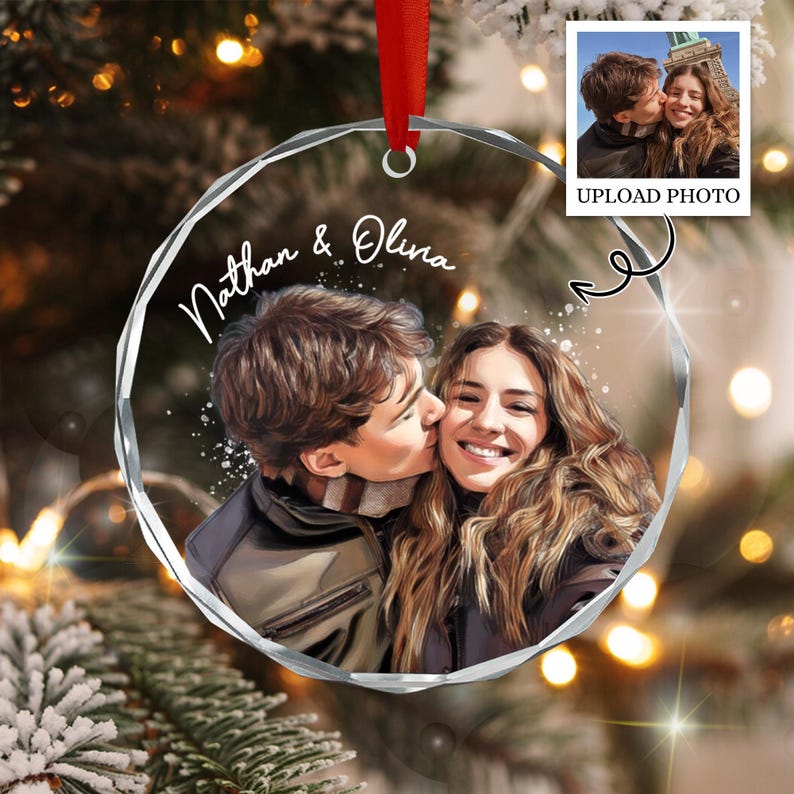 A circular, faceted glass ornament featuring a printed illustration of a couple, with the names Nathan & Olivia written in white script above them.