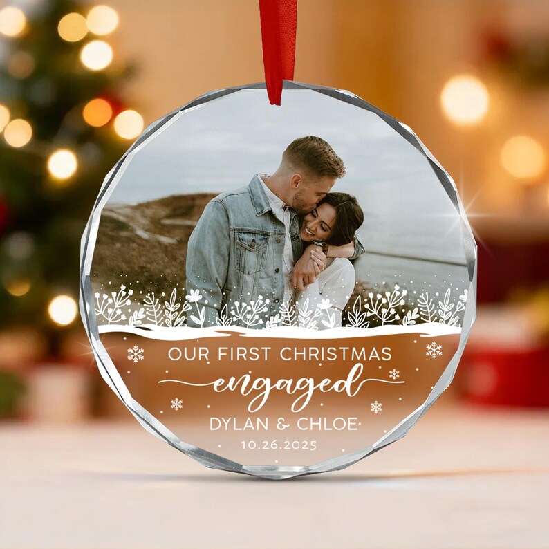 A circular glass Christmas ornament featuring a photograph of a couple embracing outdoors.